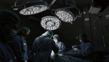 a-group-of-doctors-standing-around-a-hospital-bed.jpg A group of doctors standing around a hospital bed