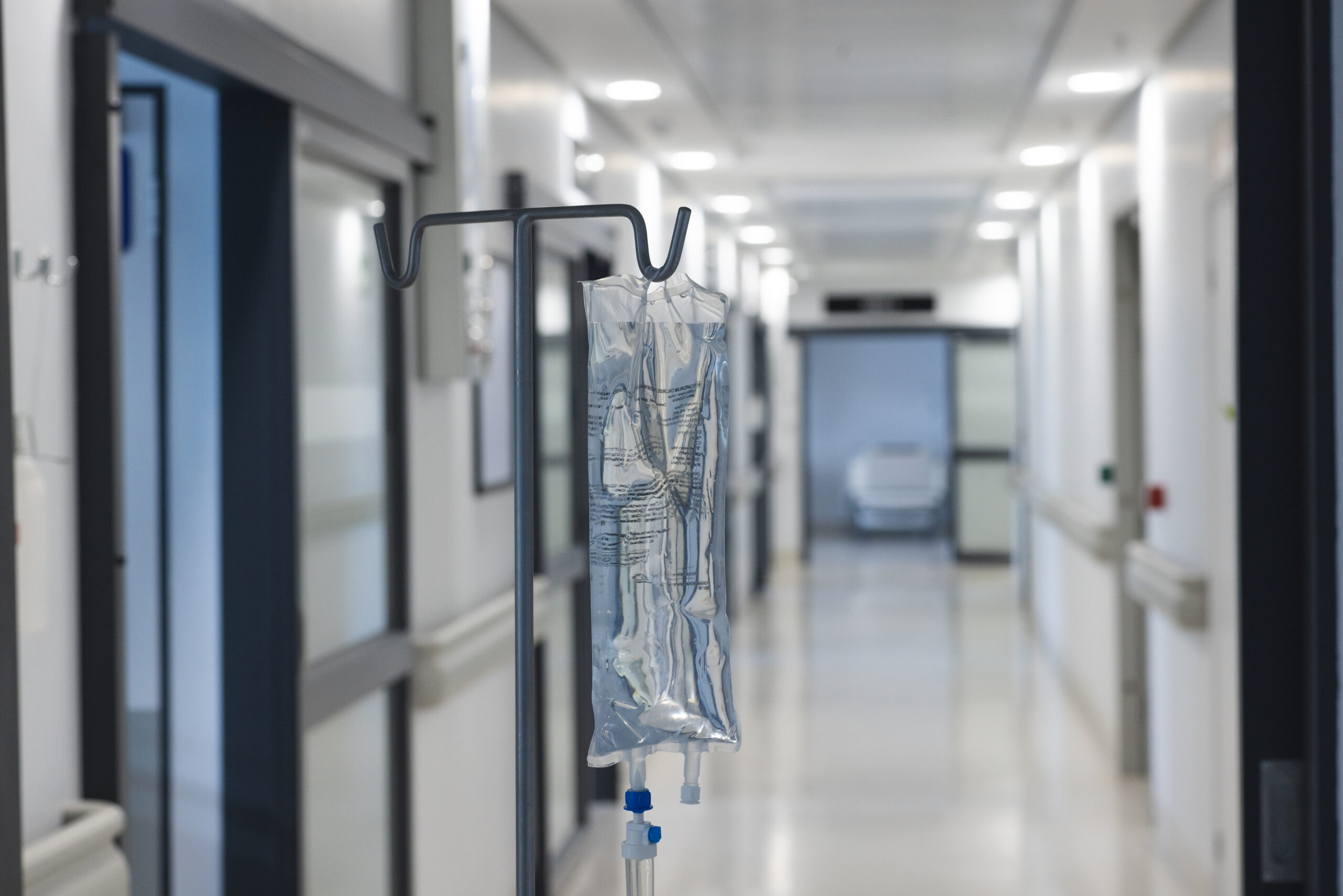 Close up of drip on hanger in hospital corridor. Medicine, healthcare and medical services, unaltered.