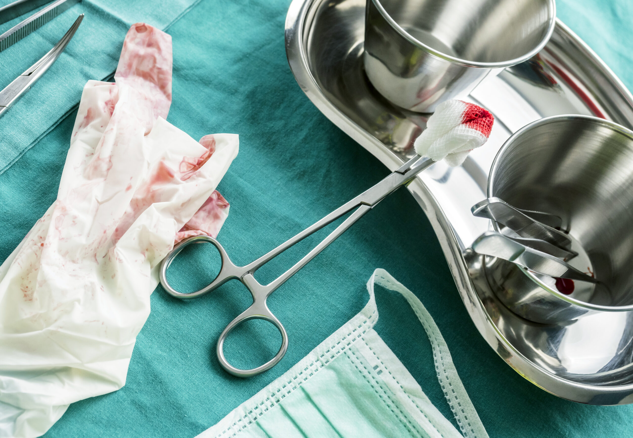 Scene details of operating theater after surgical operation, gloves spotted with blood along container tweezers and scissors of suture, conceptual image, composicon horizontal