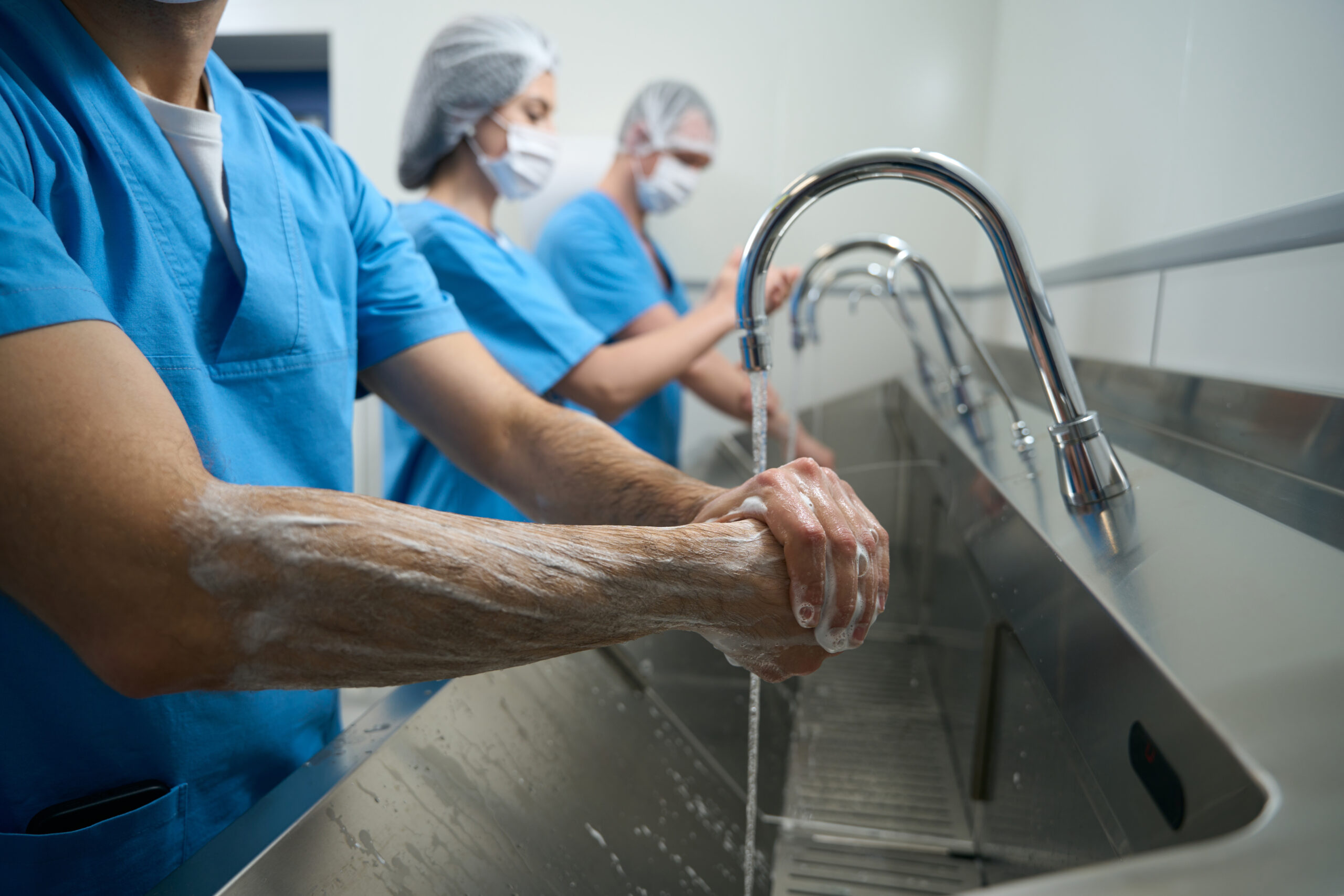 Team of surgeons thoroughly washes their hands, doctors and nurses in surgical uniforms prepare for the operation